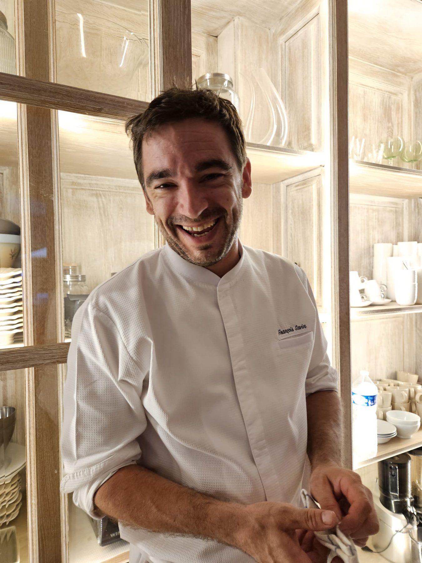 Chef François Savin in his whites, plating a layered dessert at a private dinner, dried-floral table setting with a red poinsettia.