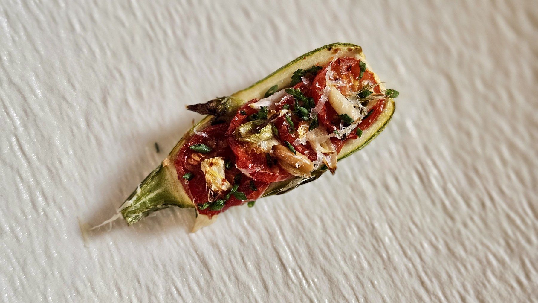 Amuse-bouche de courgette farcie sur porcelaine texturée.