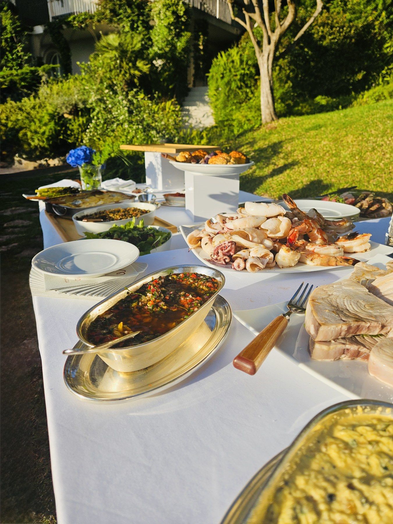 Buffet de plats à partager dans le jardin d’une villa.