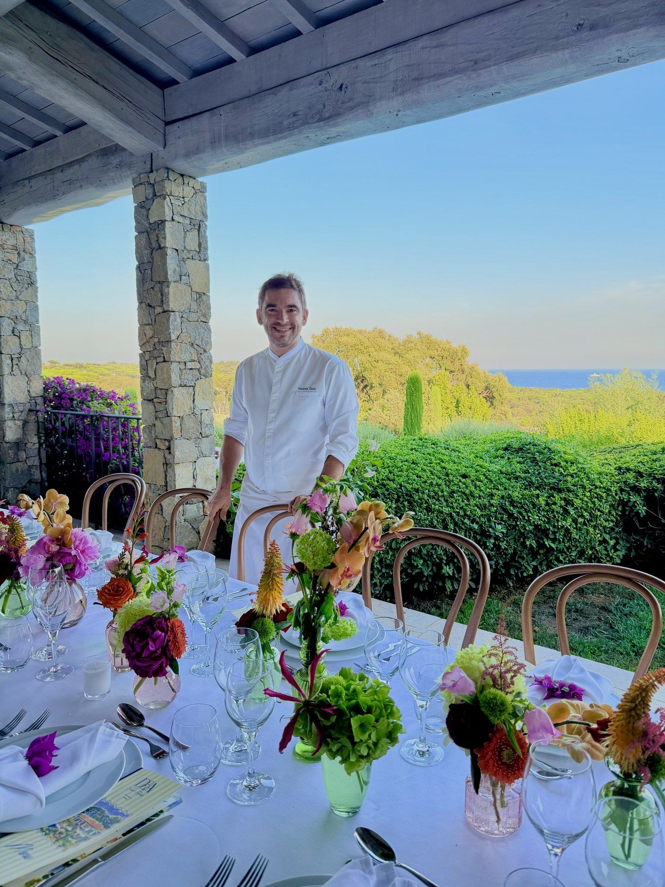 Chef François Savin en bout d’une table de banquet fleurie.