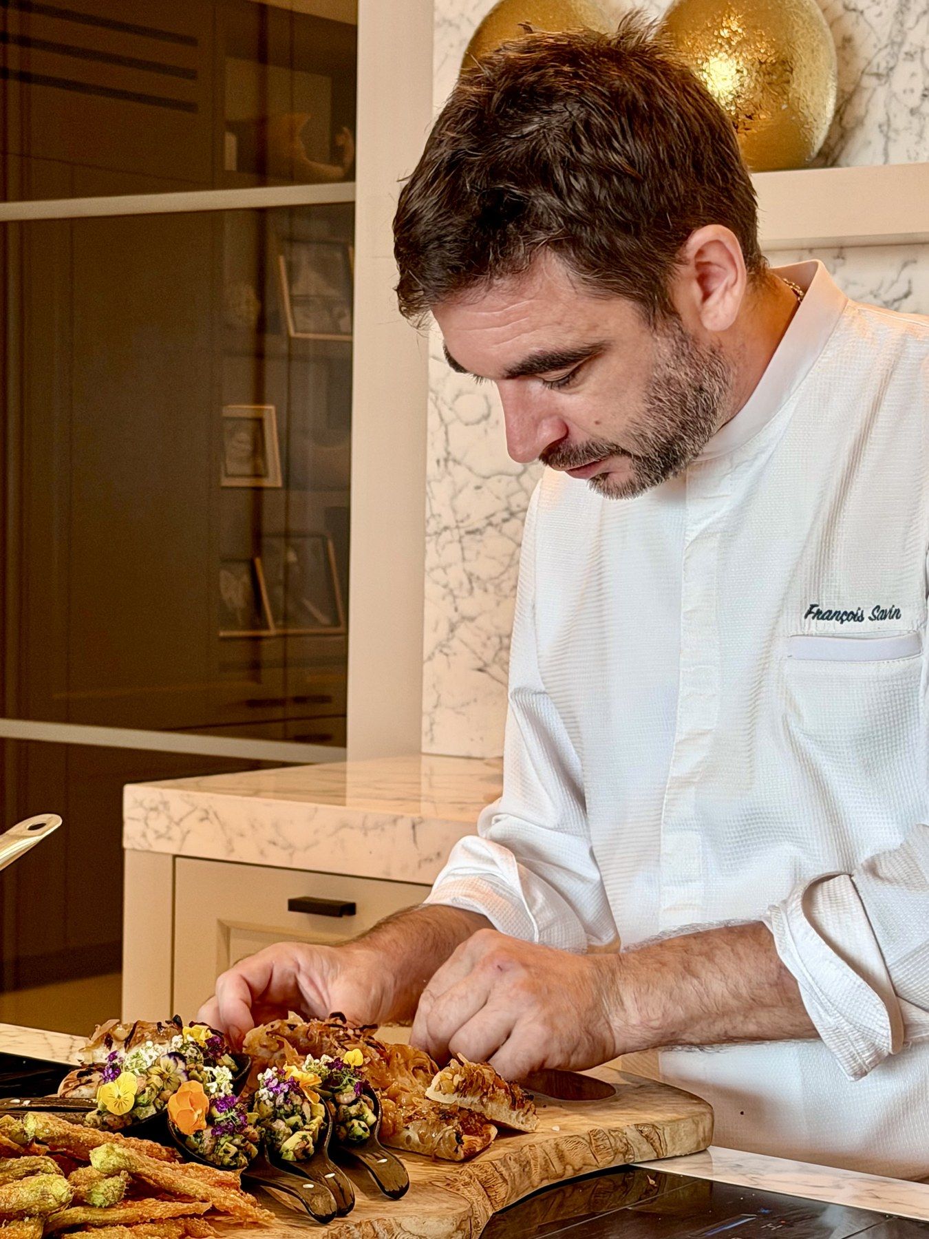 Le chef au dressage des amuse-bouches sur planche en bois d’olivier.