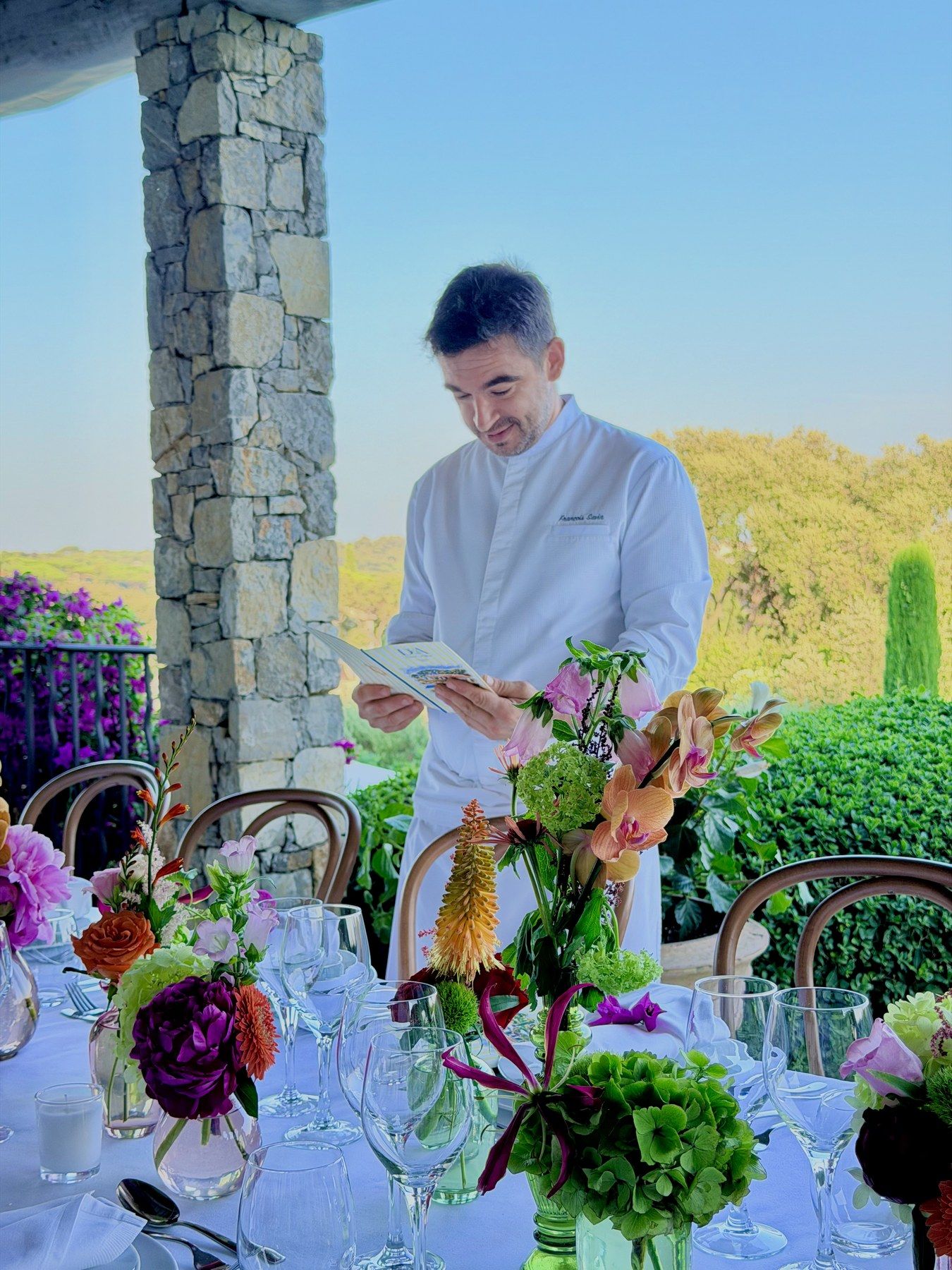 Le chef relit le menu imprimé près de la table fleurie.