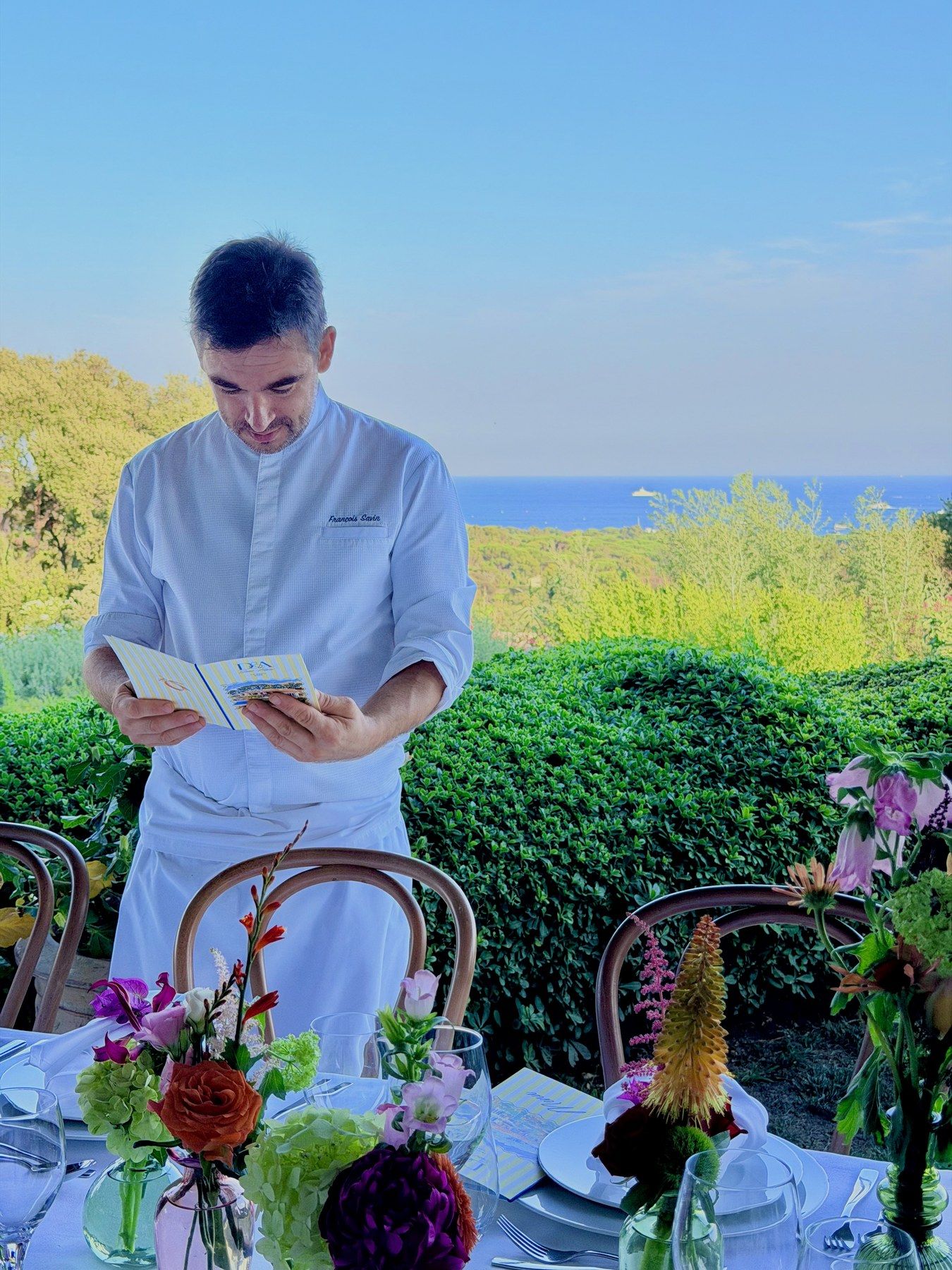 Le chef vérifie le menu en terrasse, la mer à l’horizon.