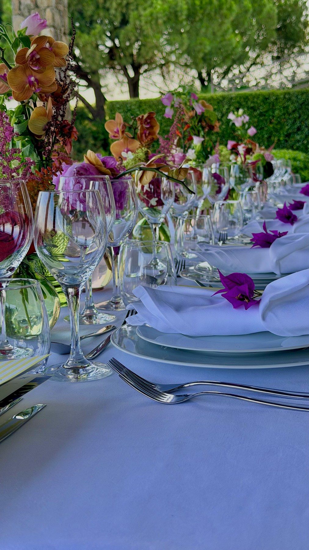 Verrerie et fleurs vives sur table en lin lavande.