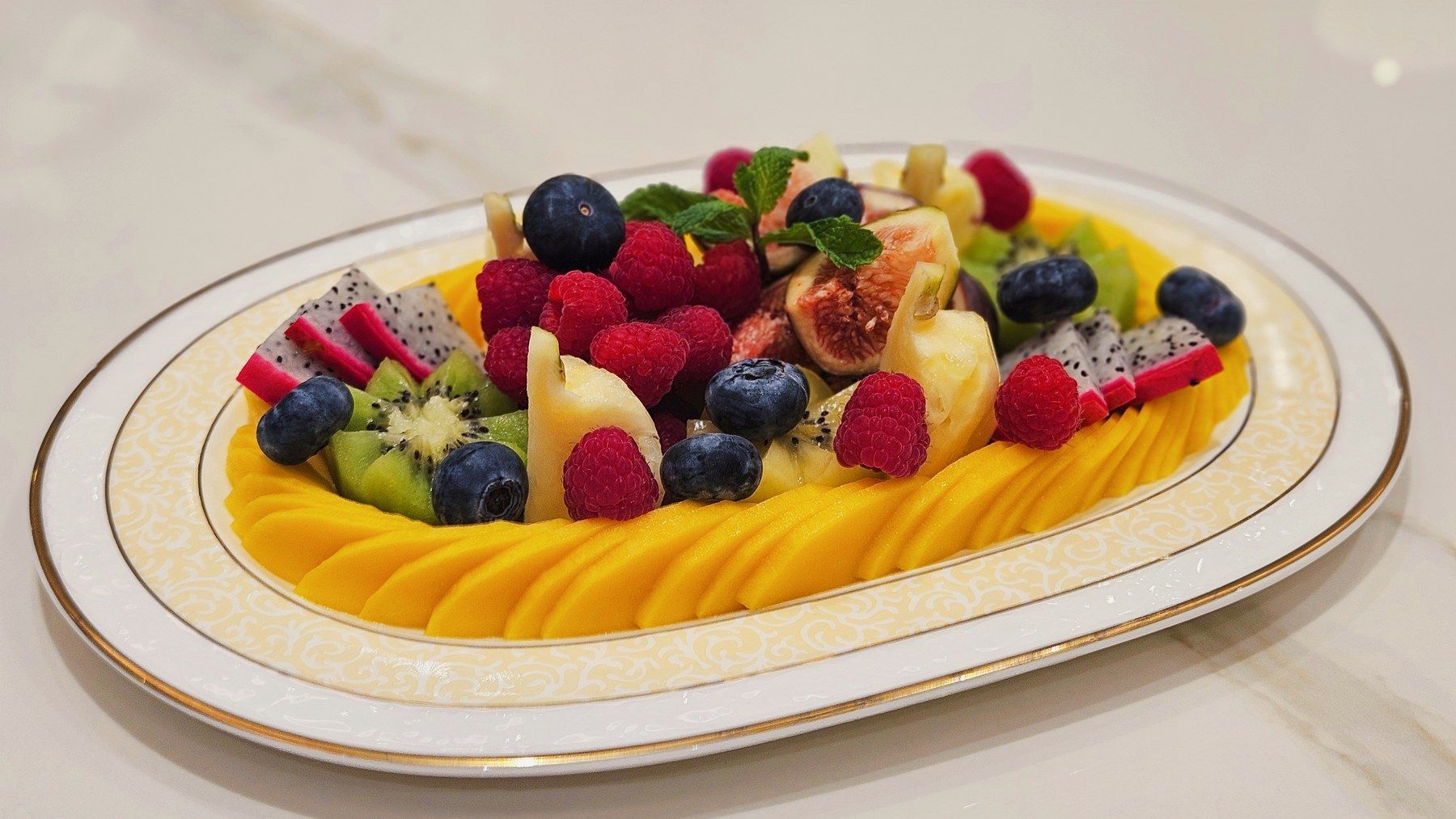 Plateau de fruits frais : mangue, baies, kiwi et fruit du dragon.