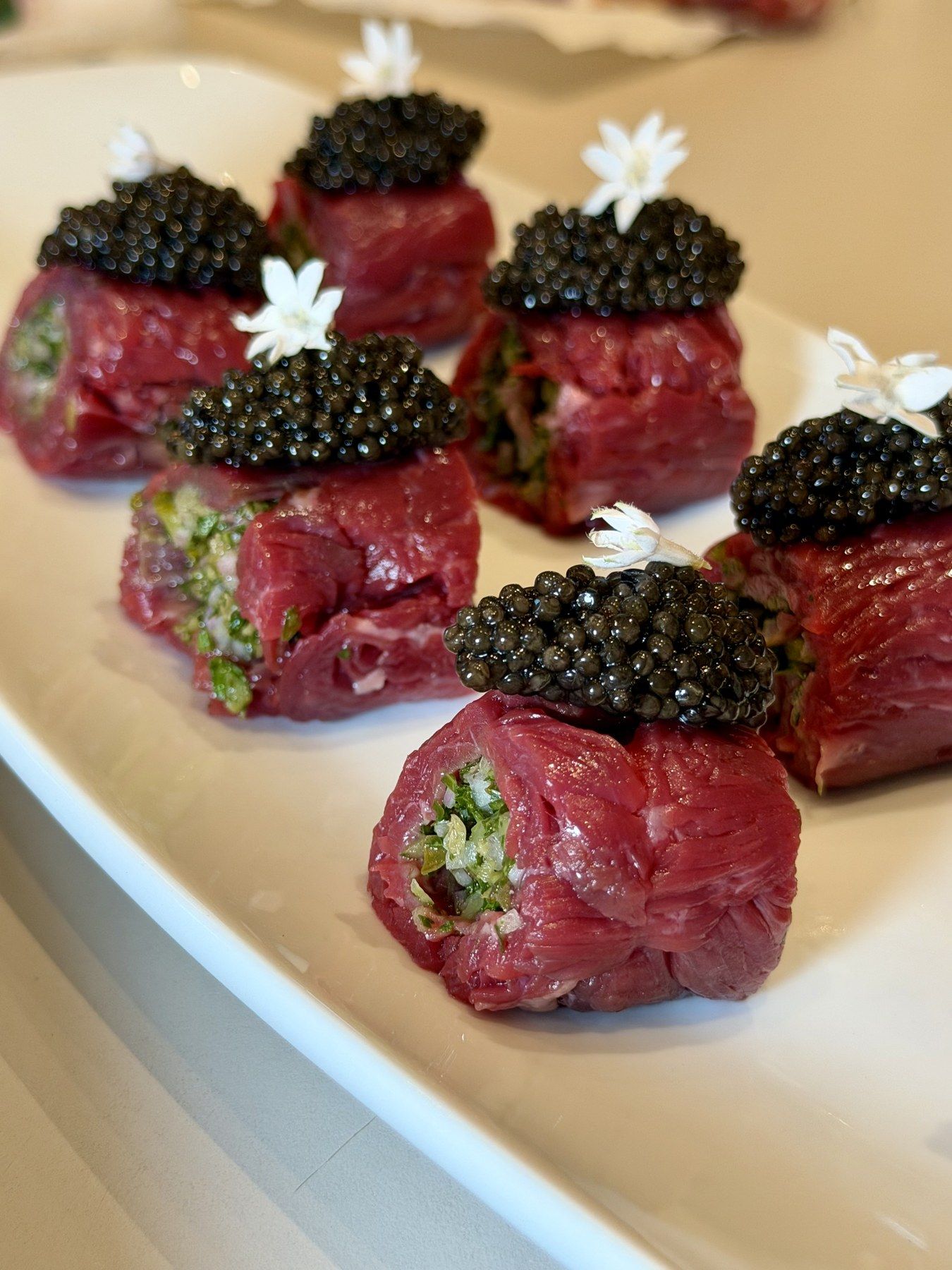 Rouleaux de carpaccio surmontés de caviar, dressés pour le service.