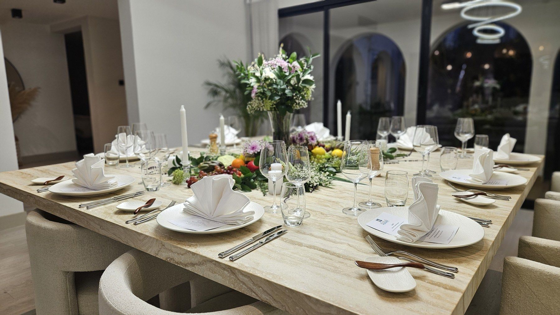 Salle à manger en marbre, table dressée de linge blanc et de fleurs.