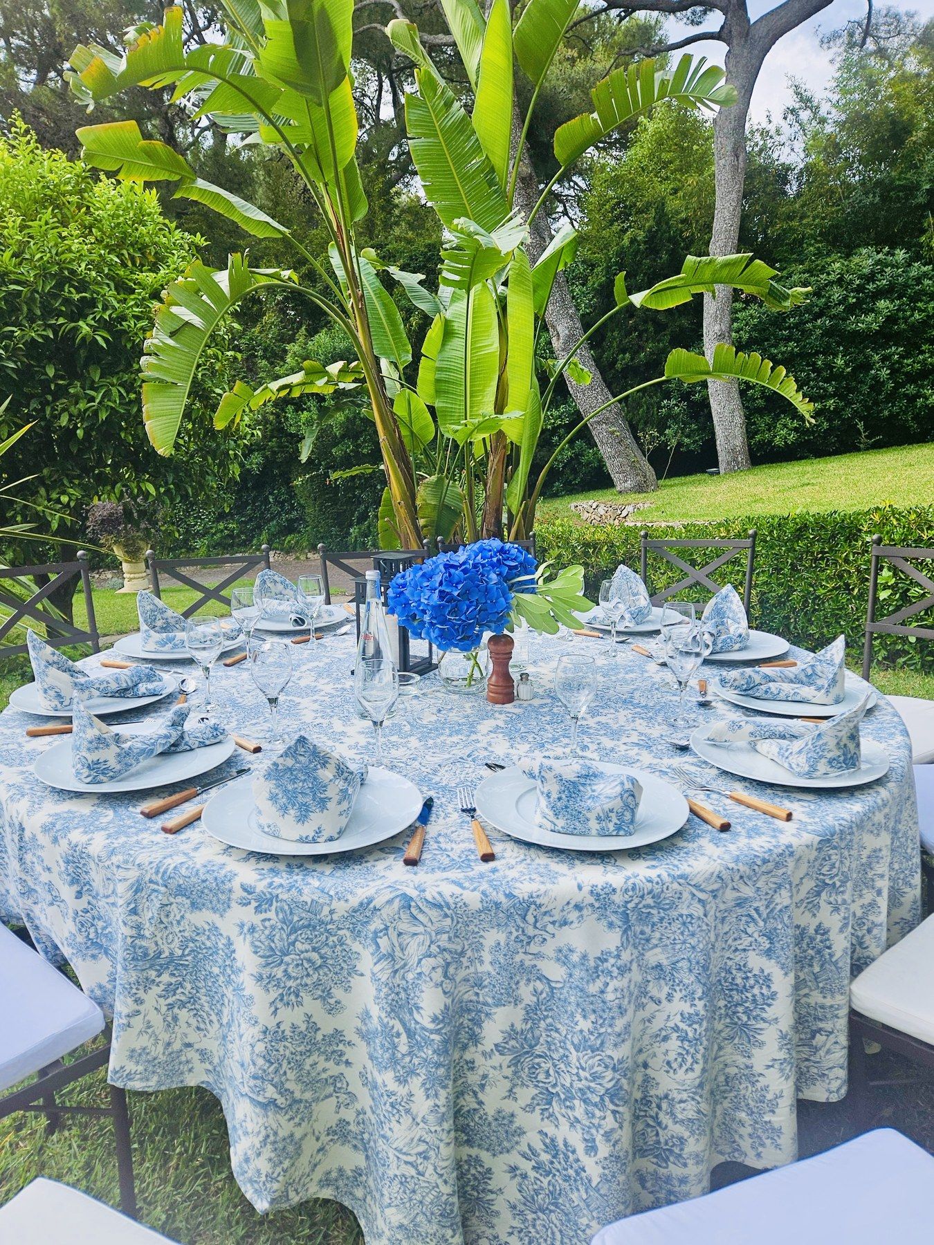 Table en toile de Jouy bleue sous les bananiers.