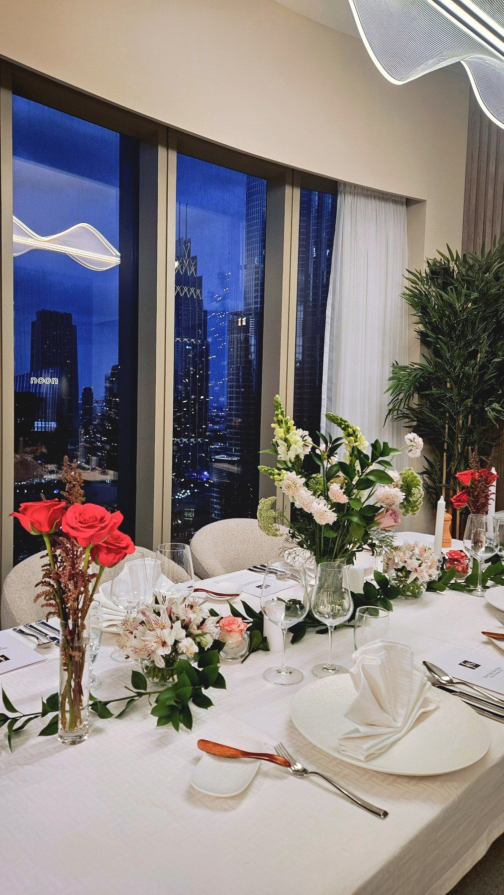 Table du soir aux roses rouges devant la baie vitrée.