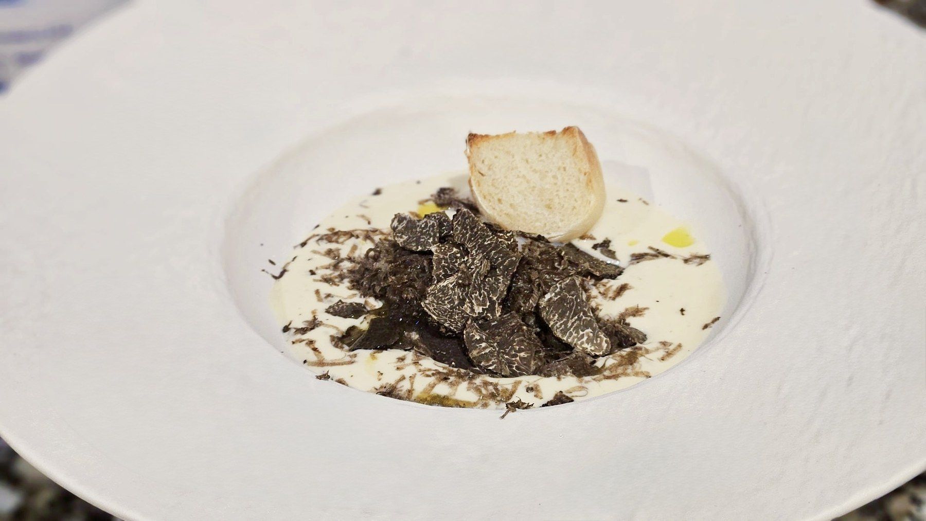 Truffe noire râpée sur base crémeuse, tuile de pain croustillante.