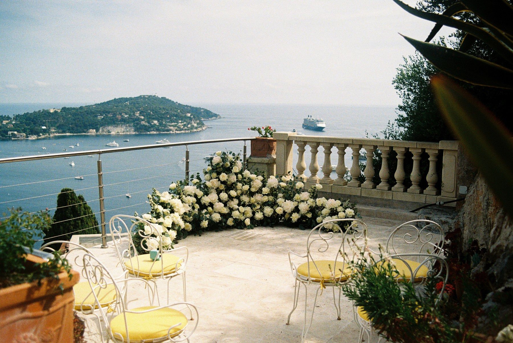 Riviera villa terrace, white-floral tablescape and sea view.